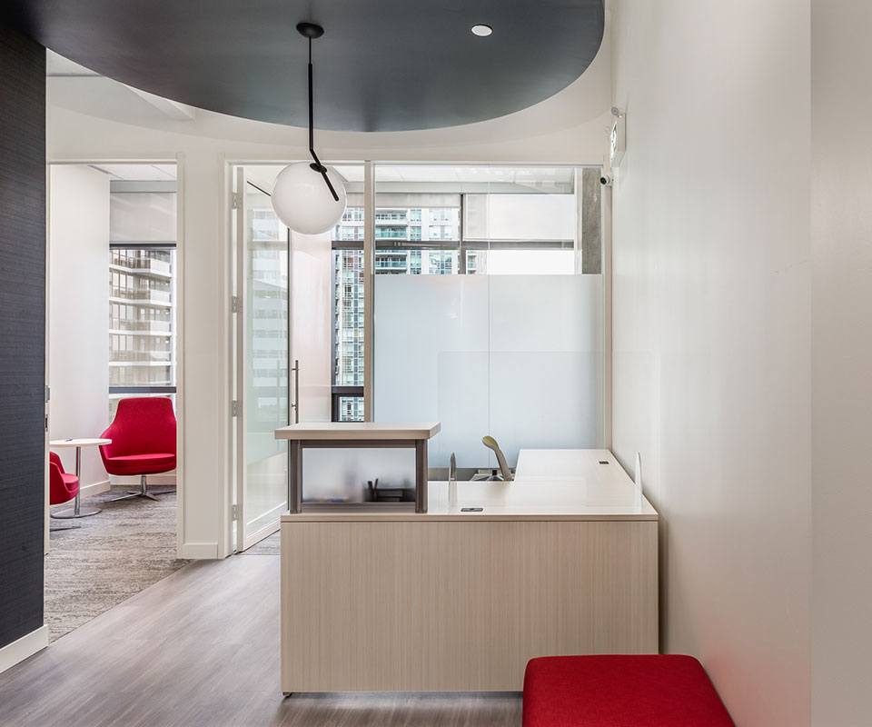 the reception desk in a bright modern office suite with large windows looking out on tall buildings