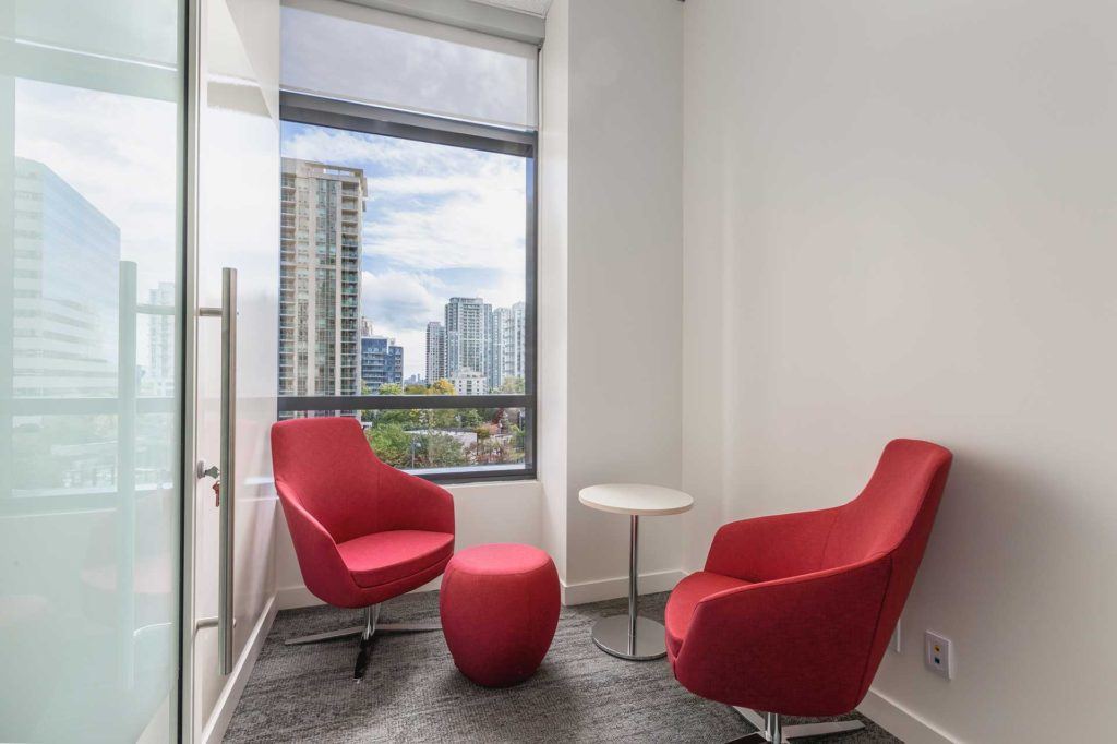 a private meeting area in a law office suite with two chairs and a table beside a window looking out on a cityscape